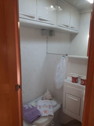 Kleines Badezimmer mit Toilette, Waschbecken und Handtüchern.